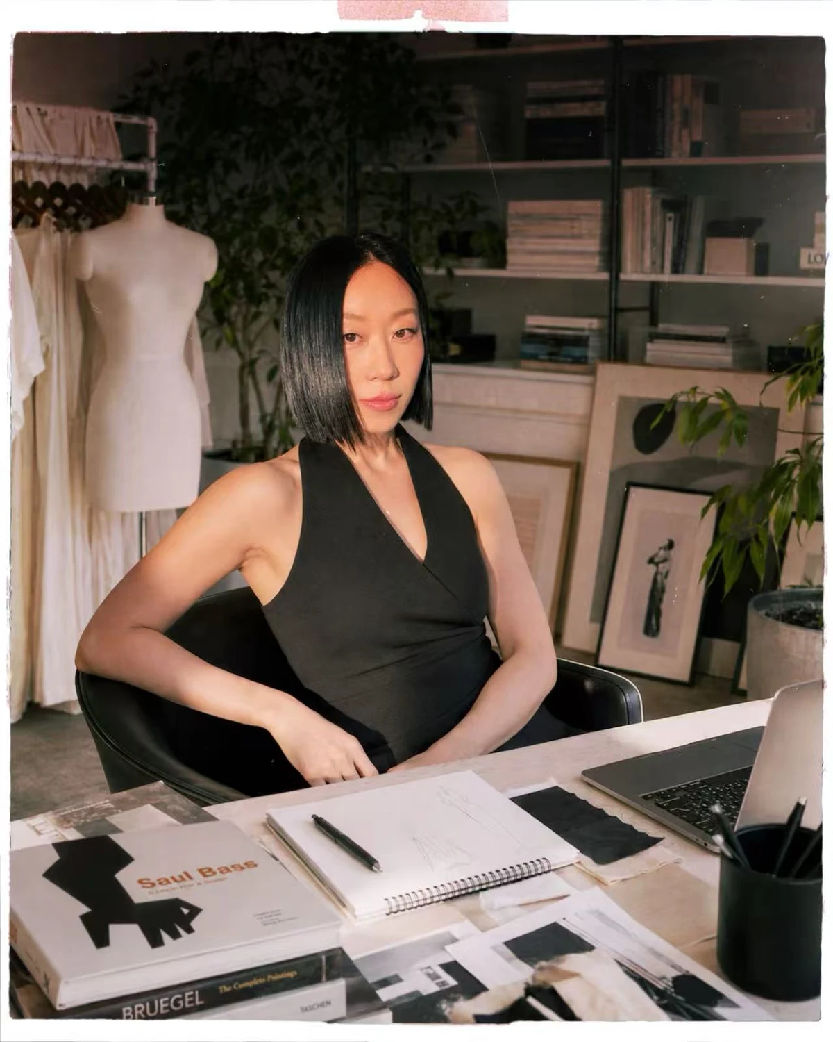 KANG YEON HYANG seated at her studio desk with books and a sketchbook.