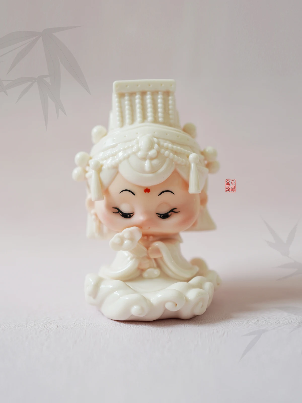 A white porcelain Mazu Tuantuan figure on a light fabric surface.